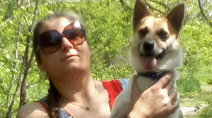 A woman in sunglasses holds a small dog