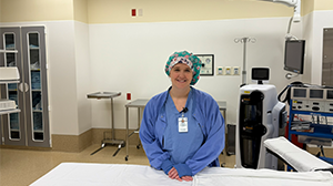 A woman wearing scrubs smiles in a hospital room