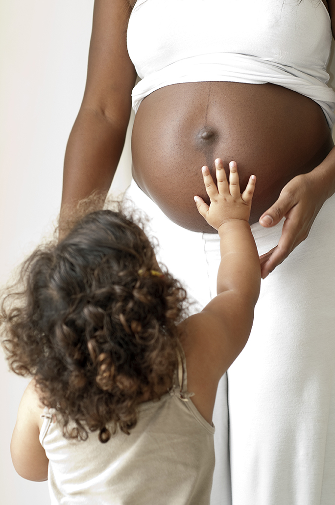 pregnant mom with child reaching up to touch belly